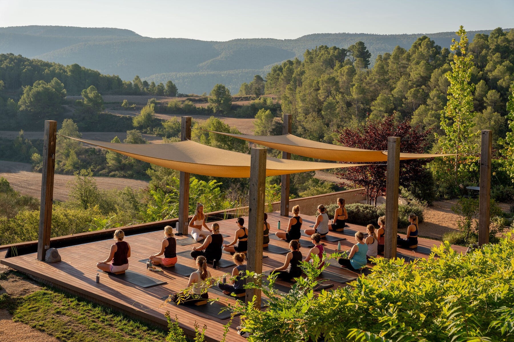 Yoga deck with women in practice at golden hour, mountain view