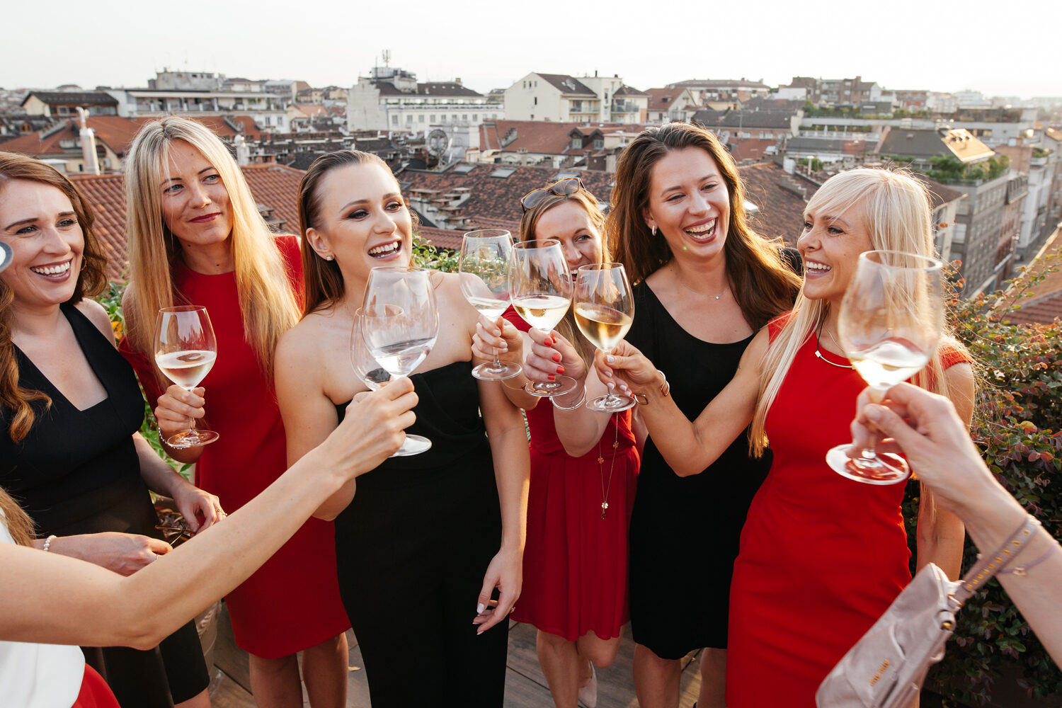 Group of women toasting together at sunset on a rooftop