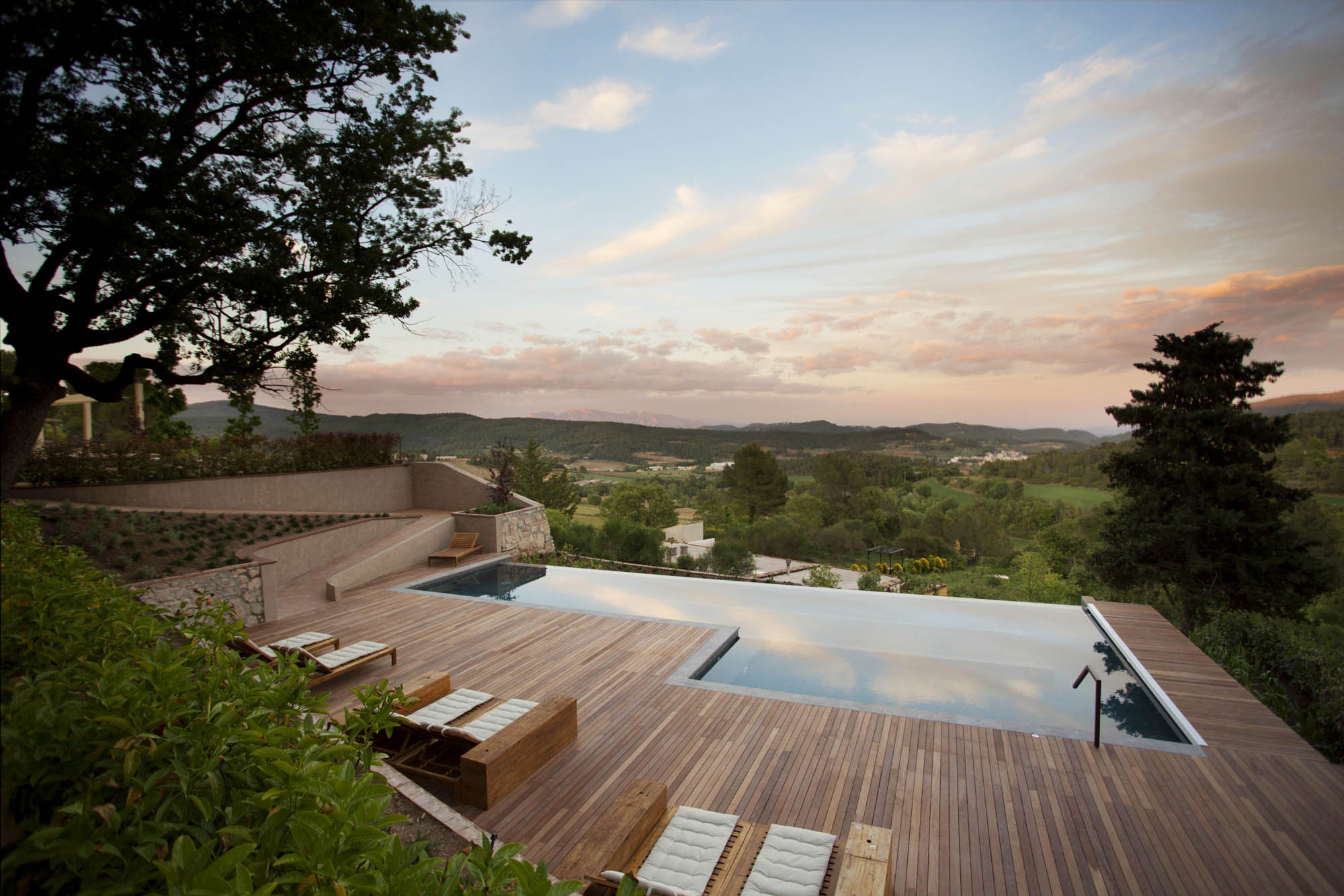 Pool deck at golden hour with view over the Penedès valley
